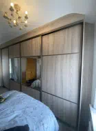 Wide 4 door sliding wardrobes in Navara Ash with a quater half quater split with the middle 2 doors having mirror instead of wood panels, installed in Redcar